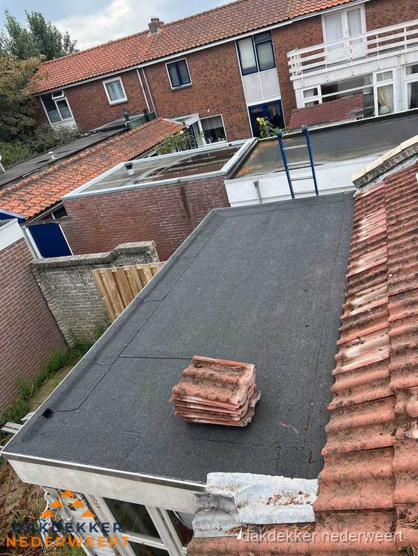 Plat dak aanbouw met bitumen naast schuin pannendak in Nederweert