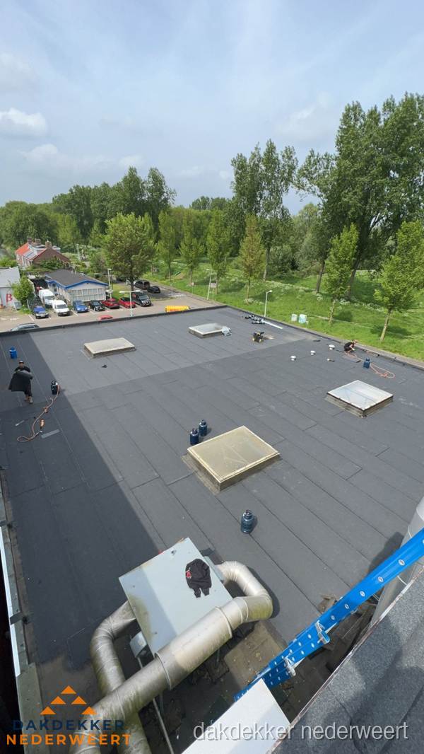 Dakdekker aan het werk op groot plat dak met bitumen in Nederweert