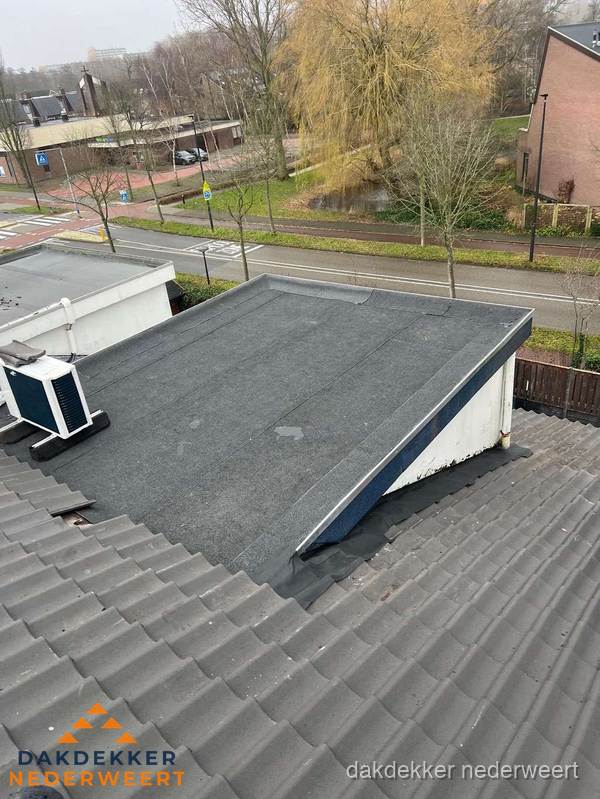 Plat dak met bitumen dakbedekking naast schuin pannendak in Nederweert