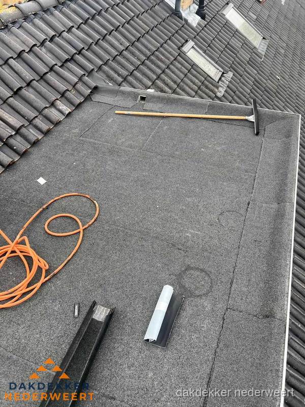 Plat dak reparatie met gereedschap en loodstroken in Nederweert