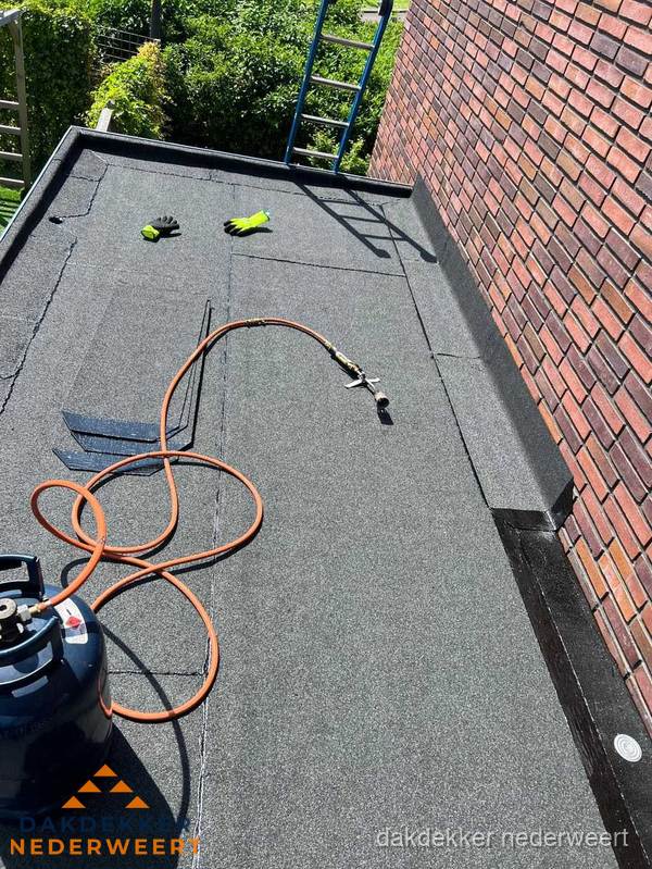 Plat dak met bitumen en brandgereedschap van dakdekkersbedrijf in Nederweert