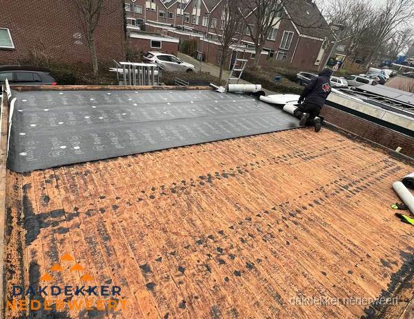 Dakdekker legt onderlaag op plat dak met houten constructie in Nederweert