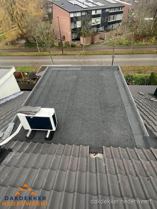Plat dak inspectie met bitumen bedekking naast schuin pannendak in Nederweert