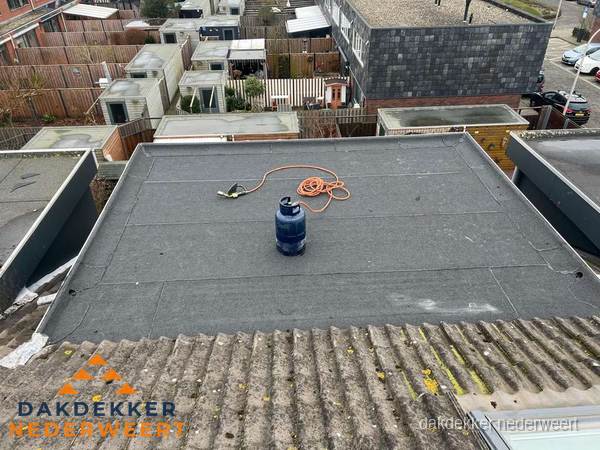 Plat dak met nieuwe bitumen dakbedekking en brandgereedschap in Nederweert
